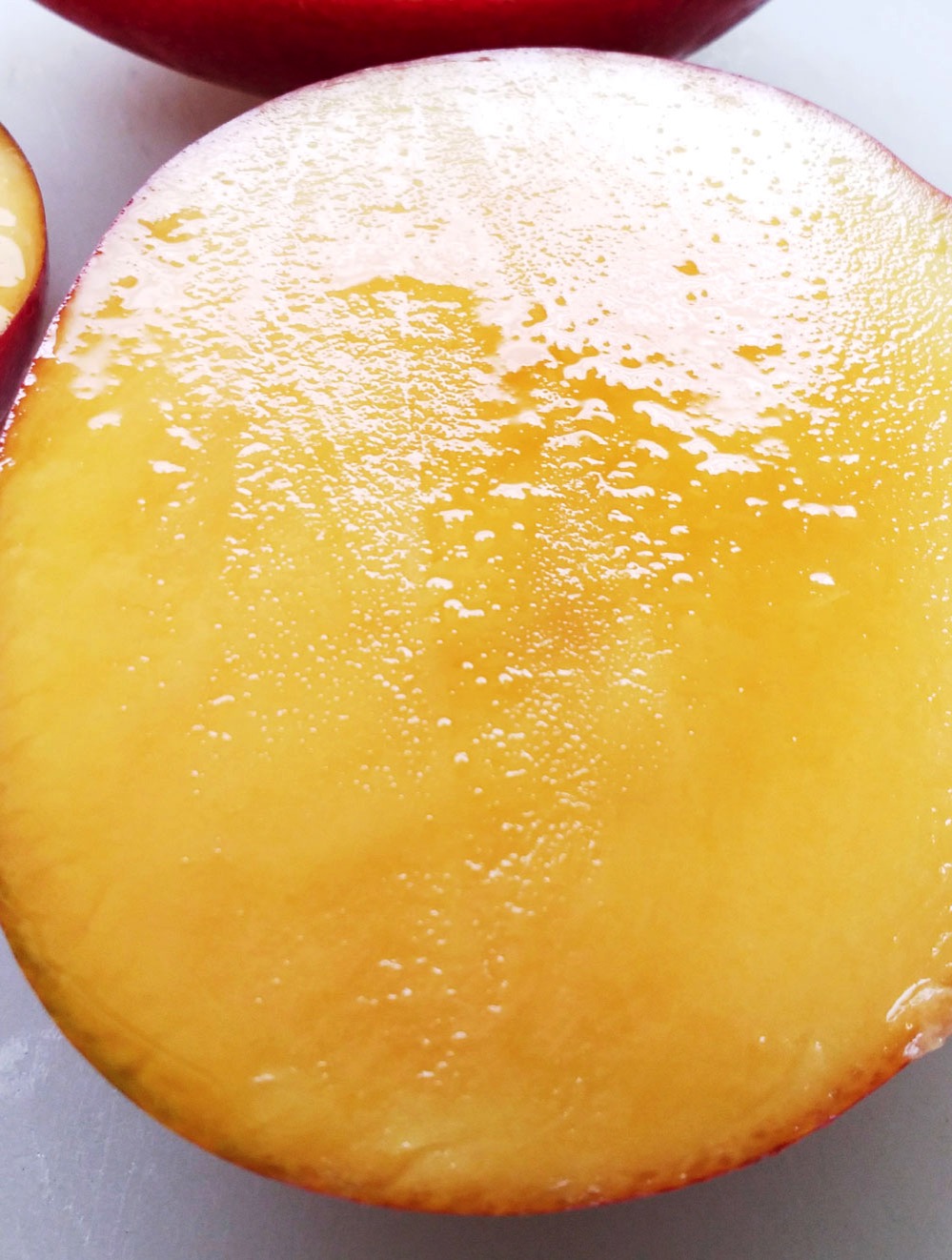 断面から果汁が溢れ出るマンゴー